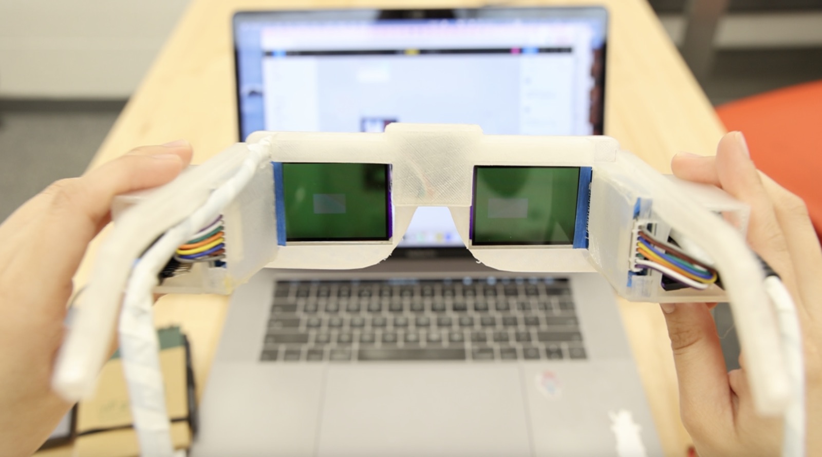 A pair of white 3D-printed AR glasses with rectangular electrochromic lenses, worn while reading